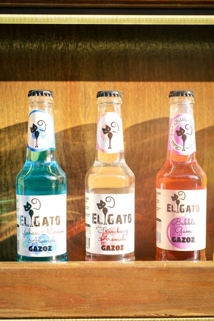Three vibrant soda bottles arranged on a wooden shelf, perfect for beverage ads.